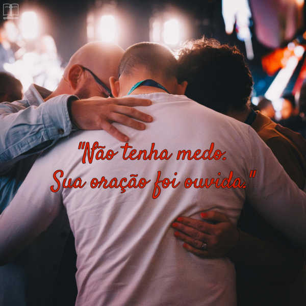 Qual será a sua reação quando Deus finalmente responder à sua oração? Você dirá "já estava na hora" ou O adorará com gratidão? Três homens em círculo, com as cabeças juntas e abraçados, rezam. A parte de trás da camisa de um deles diz: Não tenha medo. Sua oração foi ouvida.